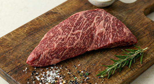 Raw steak on a wooden cutting board with rosemary and spices